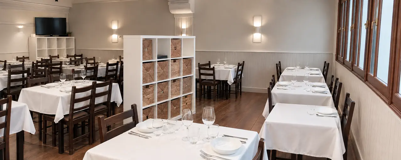 Sala del restaurante con mesas puestas, mantequillos blancos y copas de vino