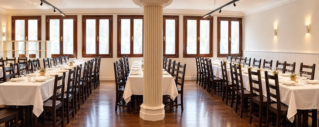 Sala amplia con mesas largas para grupos, columna central y ventanales de madera